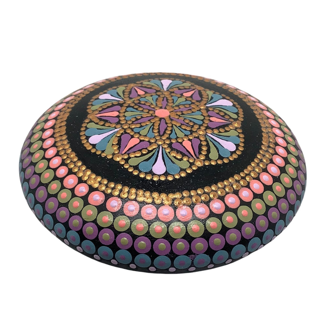 Hand-painted Circle of Life mandala stone in pink, gold, green, and lavender on a black base, with glossy varnish finish.