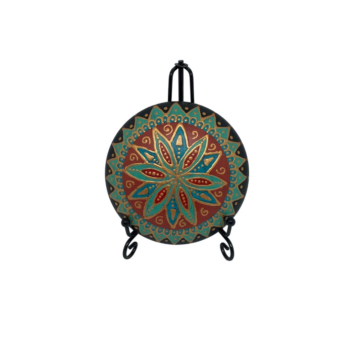 Close-up of a unique mandala stone in vibrant turquoise, red, and gold hues, coated with a protective varnish.