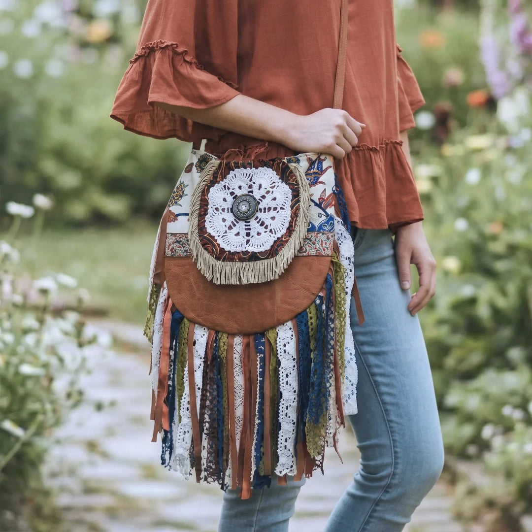 Person holding a colorful handbag with floral patterns and fringes in a garden setting