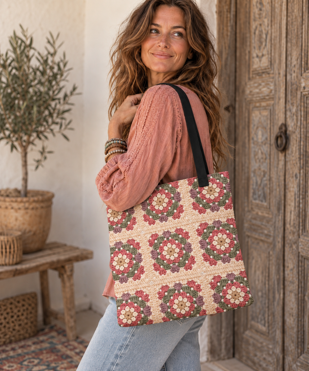 Boho woman carrying a floral granny square printed tote bag by a rustic wooden door