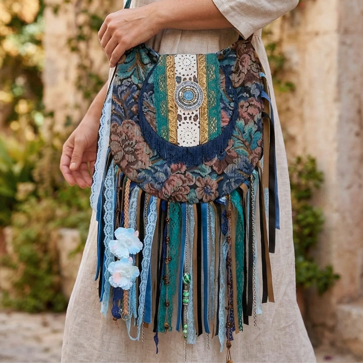 Decorative bag with floral patterns and tassels held by a person outdoors.