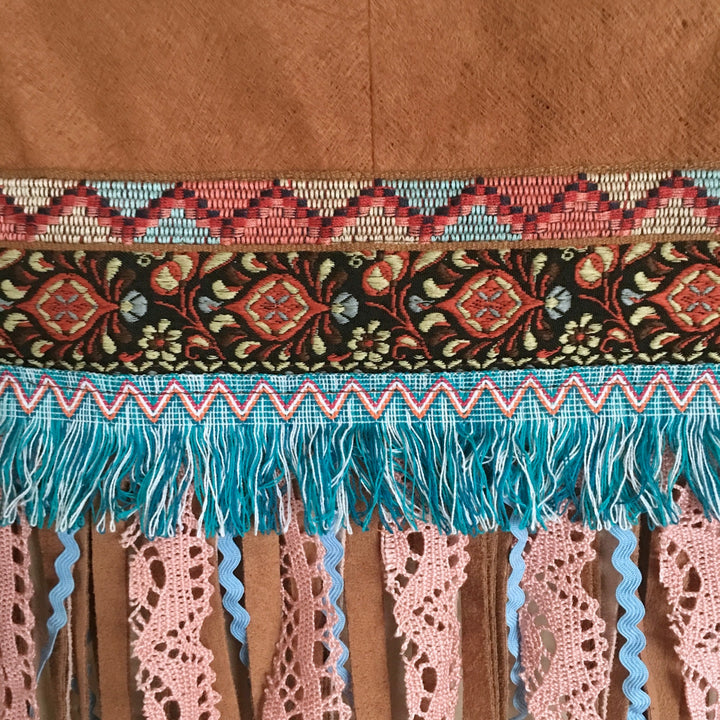Close-up of decorative fabric with intricate patterns and fringes on a brown background