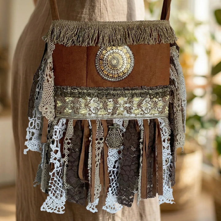 Brown handbag with decorative elements on a blurred background