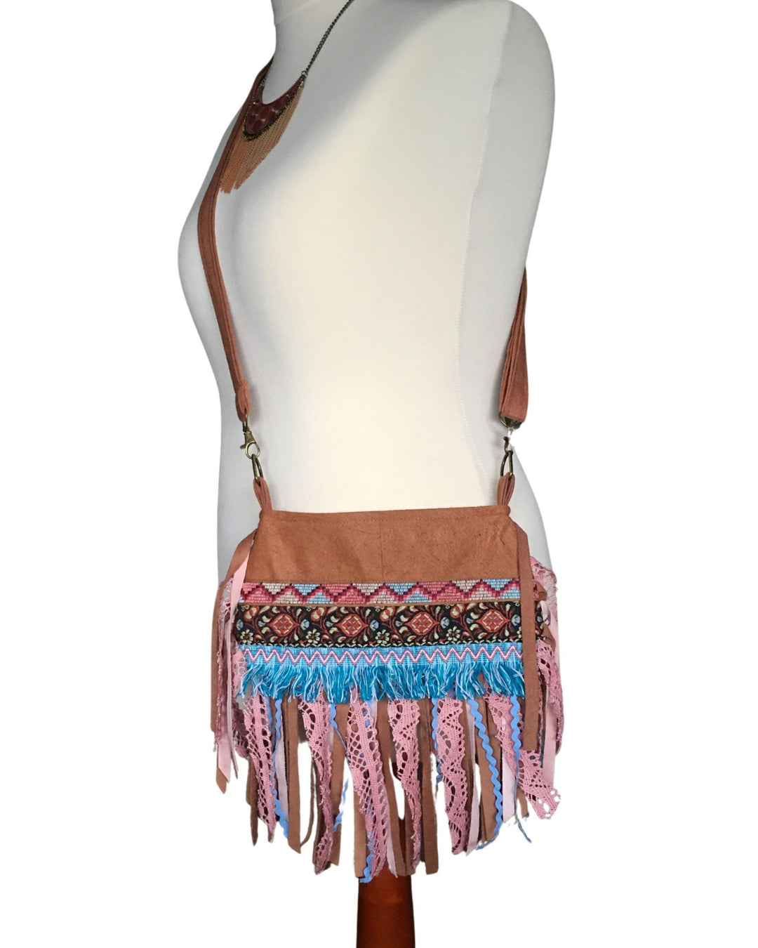 Brown crossbody bag with colorful fringe and patterned accents on a mannequin.
