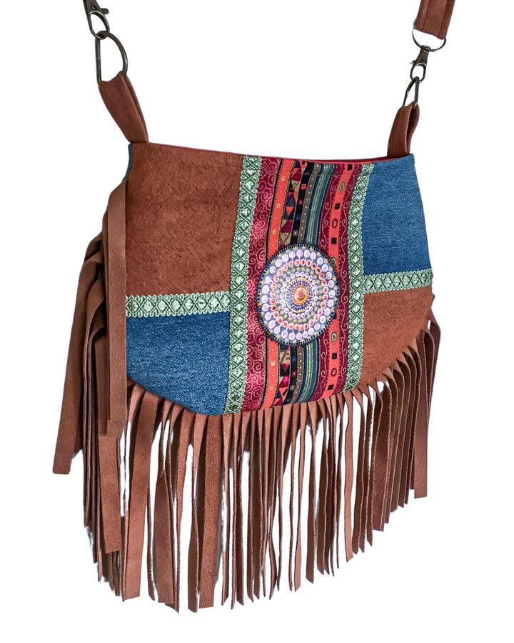 Brown barkcloth handbag with colorful patchwork design and fringes on a white background