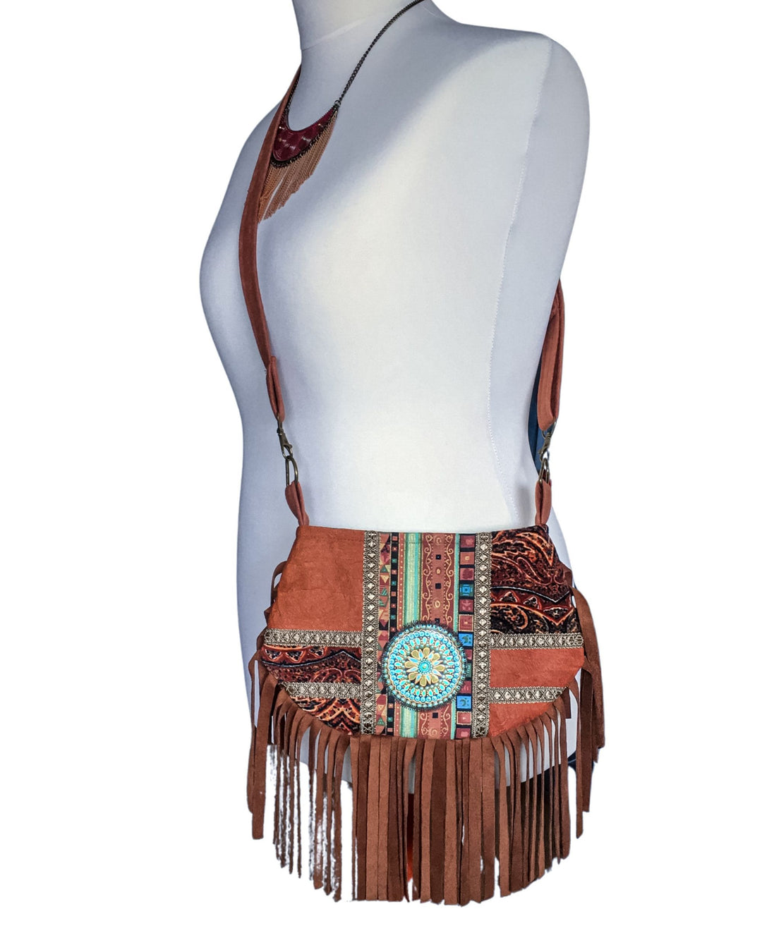 Brown barkcloth crossbody bag with fringe and decorative elements on a mannequin.