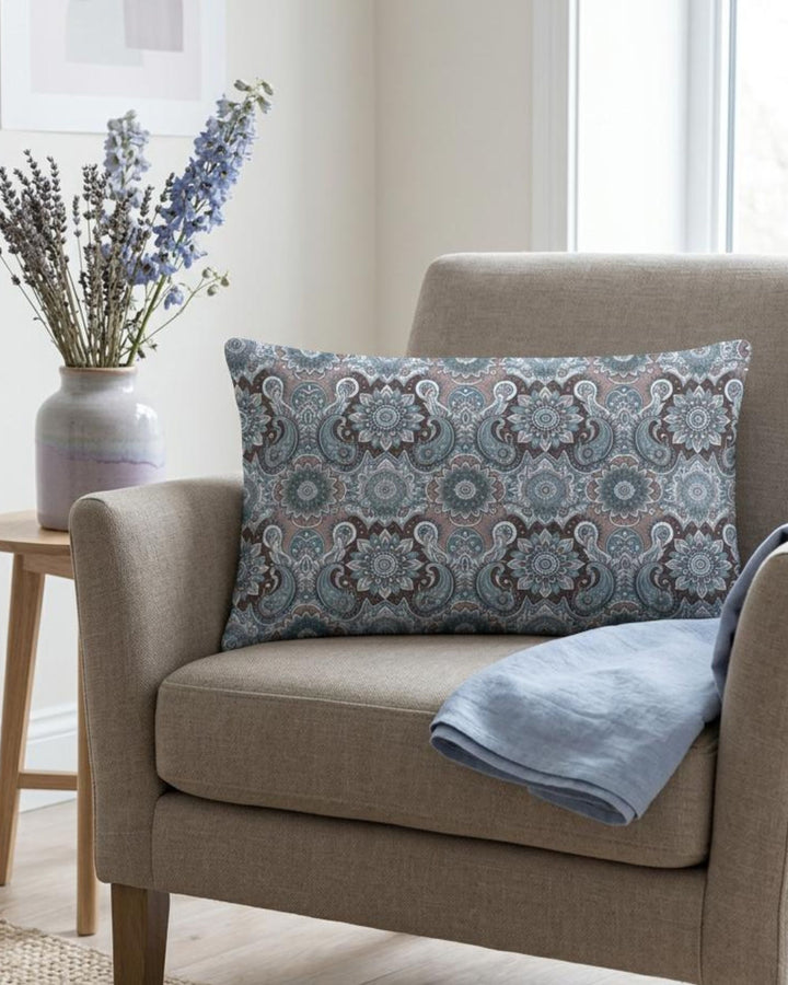 Boho lumbar pillow cover with grey, soft blue and muted lavender mandala paisley pattern styled on a beige armchair in a calm neutral interior