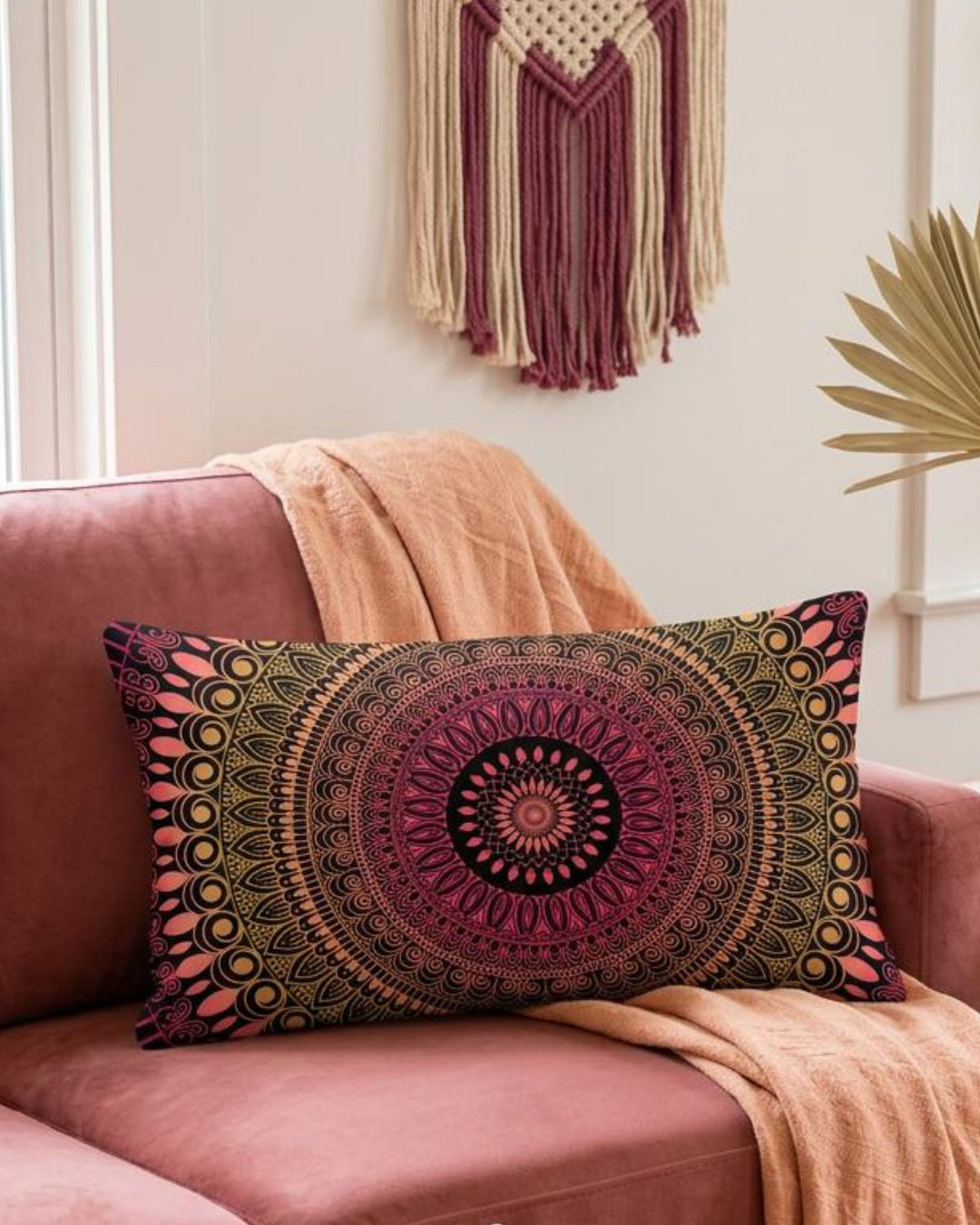 Boho lumbar pillow cover in pink, coral, gold and black mandala design styled on a dusty rose sofa in a warm colorful boho interior