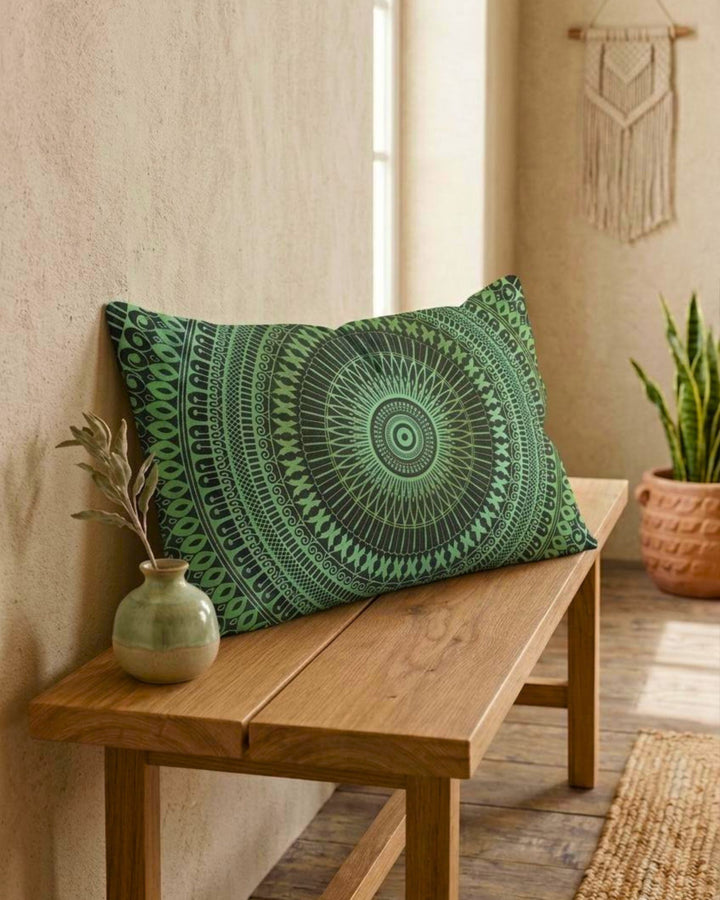 Green mandala lumbar pillow cover on a wooden bench, softly angled forward in a calm boho interior with textured beige wall, ceramic vase and plant, natural daylight and earthy tones
