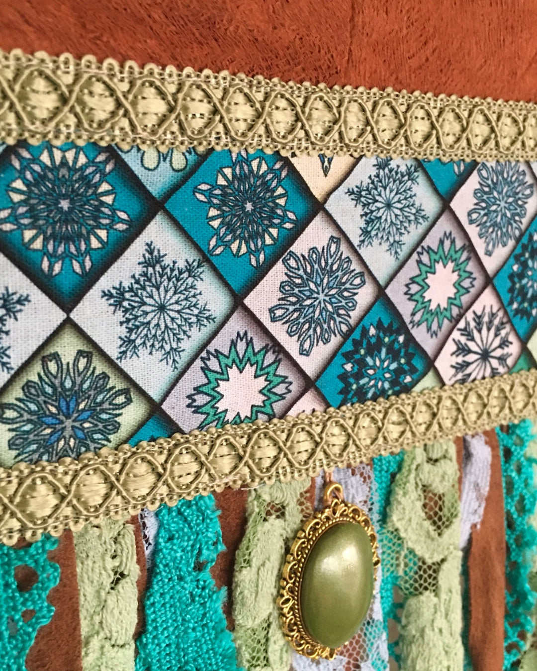 Decorative fabric with geometric patterns and a gold pendant on a textured background