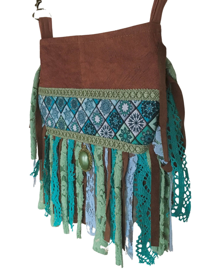 Brown barkcloth bag with green and blue patterned fabric and fringes on a white background
