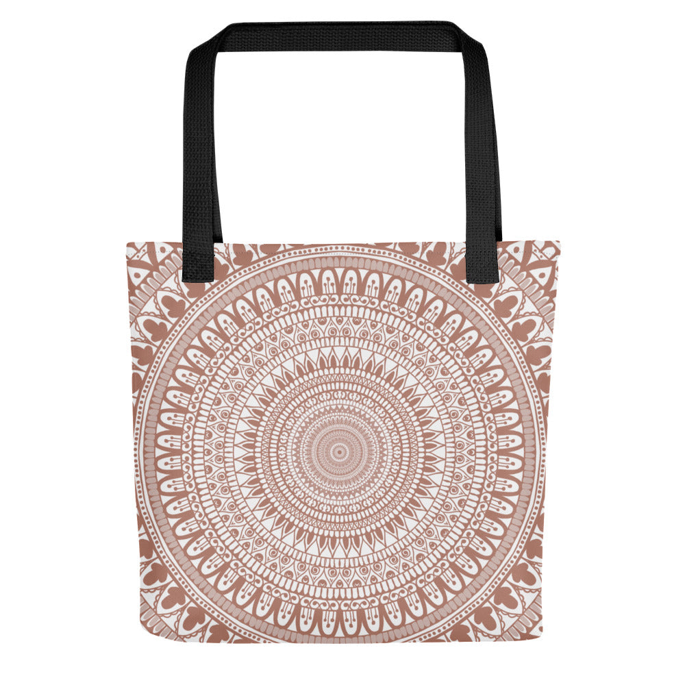 A tote bag featuring a mandala design in white on a terracotta background