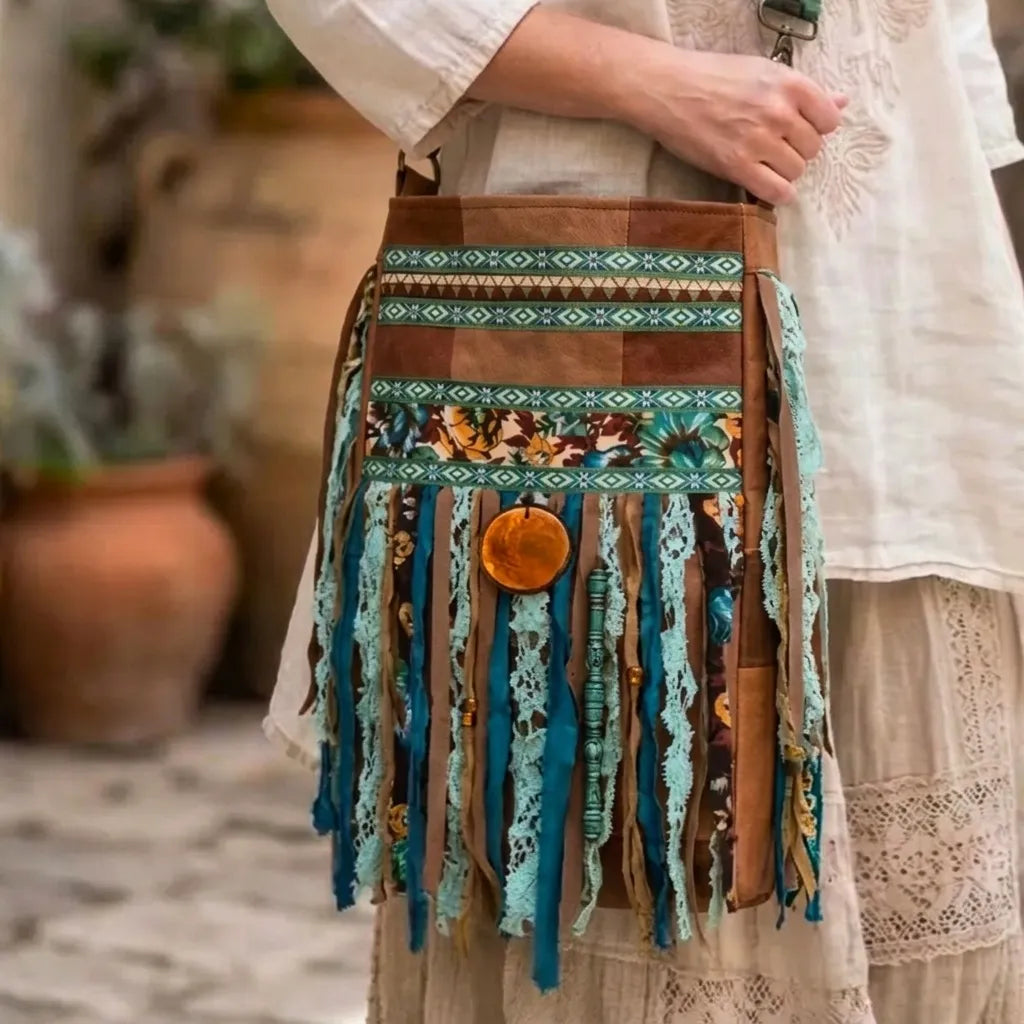 Bohemian handgemaakte crossbody tas met franjes in turquoise en bruintinten, gedragen op de heup, met kantdetails en vintage stoffen in een natuurlijke Ibiza stijl setting