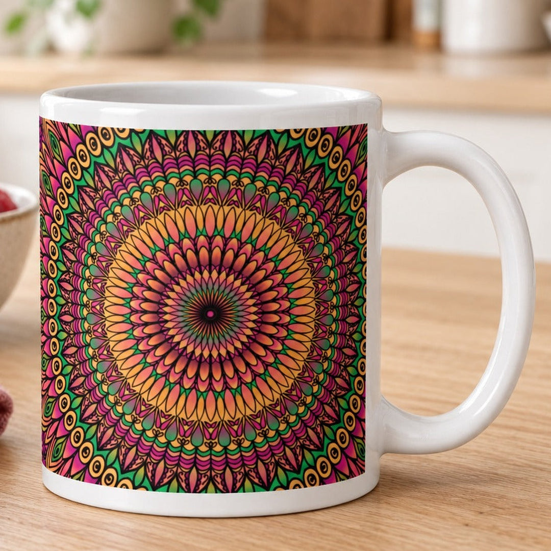 Close-up lifestyle photo of white ceramic mug with orange pink and green floral mandala.