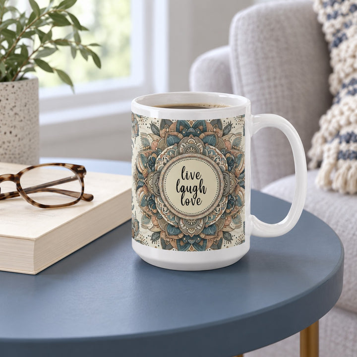 15 oz Live Laugh Love blue mandala mug on a blue side table beside a book and reading glasses.