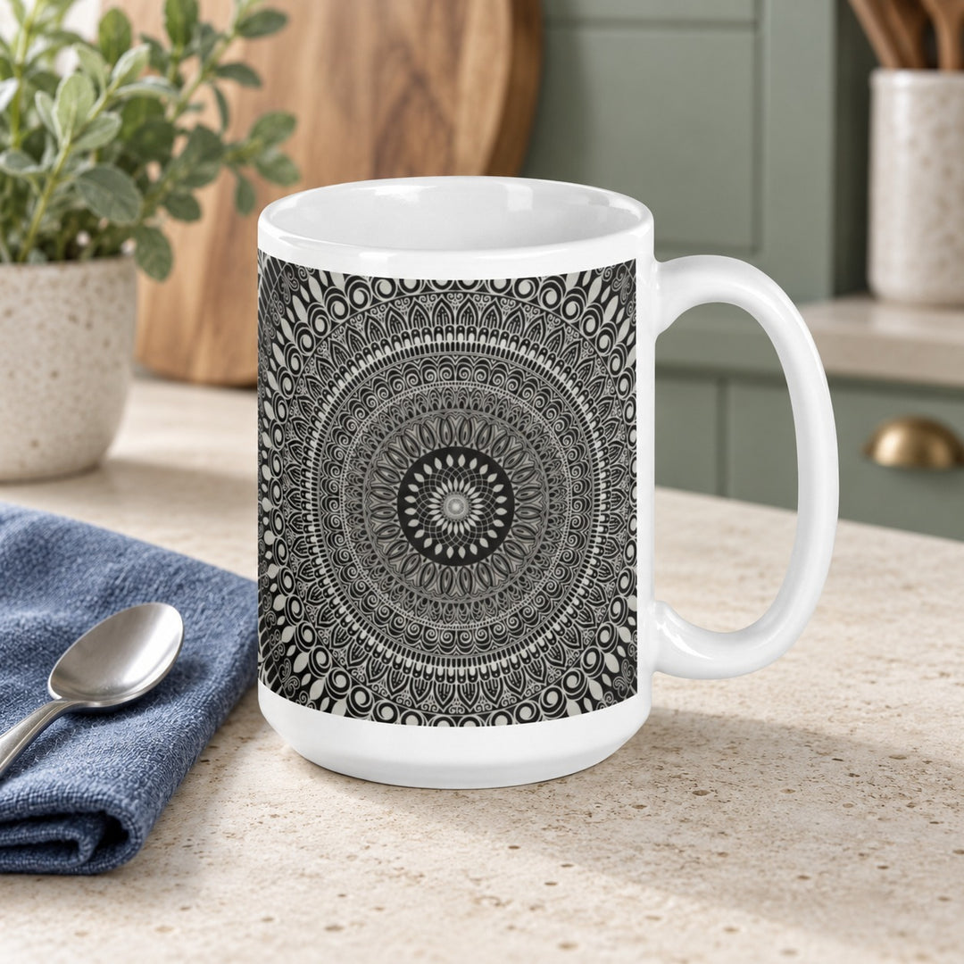 15 oz white ceramic mug with gray and black mehndi mandala on a stone kitchen counter with a blue napkin.