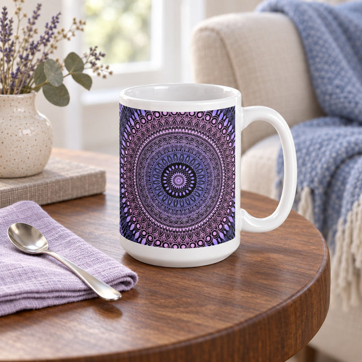 15 oz white ceramic mug with pink and lavender mehndi mandala on a wooden side table beside a blue throw.