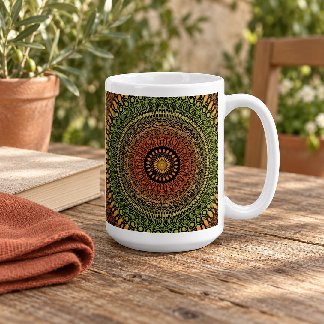 15 oz white ceramic mug with terracotta and green mehndi mandala on a wooden courtyard table beside a book.