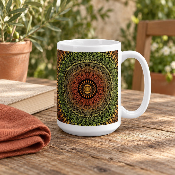 15 oz white ceramic mug with terracotta and green mehndi mandala on a wooden courtyard table beside a book.