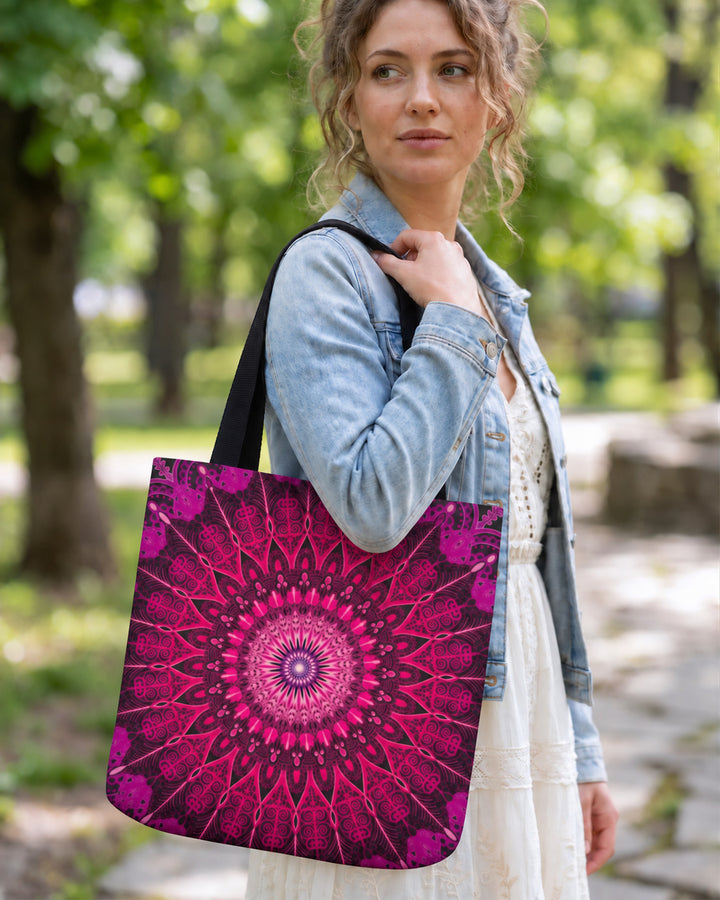 Pink and black mandala tote bag worn by a woman in a park